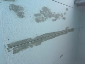 外壁表面のひび割れや欠損部をパテなどで補修している写真